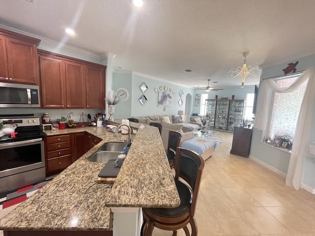 kitchen featuring sink, kitchen peninsula, a kitchen bar, ceiling fan with notable chandelier, and appliances with stainless steel finishes