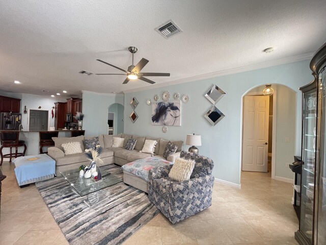 tiled living room with a textured ceiling, ceiling fan, and crown molding