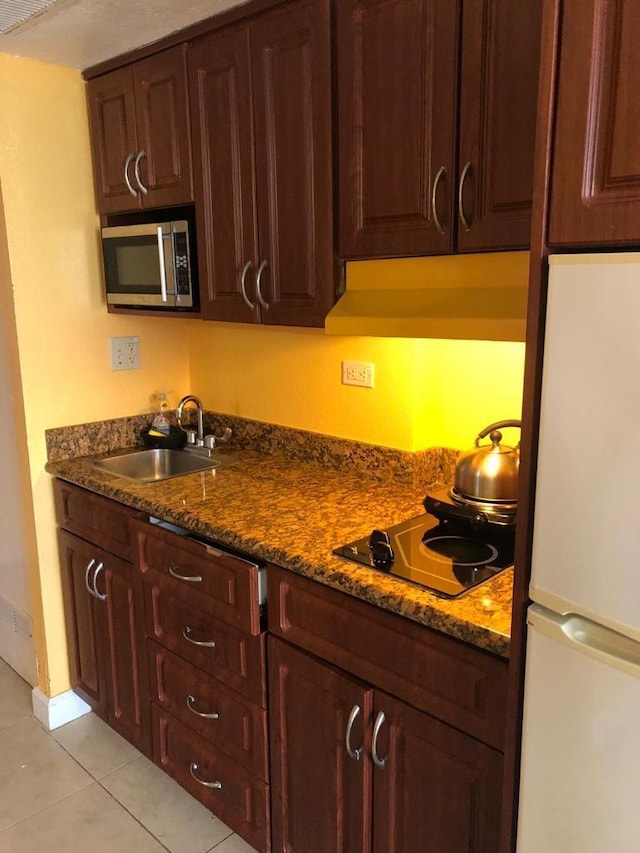 kitchen with custom range hood, sink, white fridge, and dark stone countertops