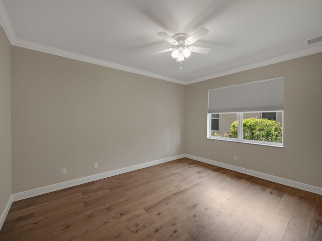 empty room with visible vents, a ceiling fan, wood finished floors, crown molding, and baseboards