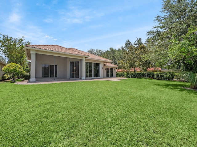 back of property featuring a yard, stucco siding, a tiled roof, and a patio