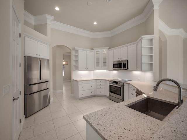 kitchen with sink, appliances with stainless steel finishes, white cabinetry, and light stone counters