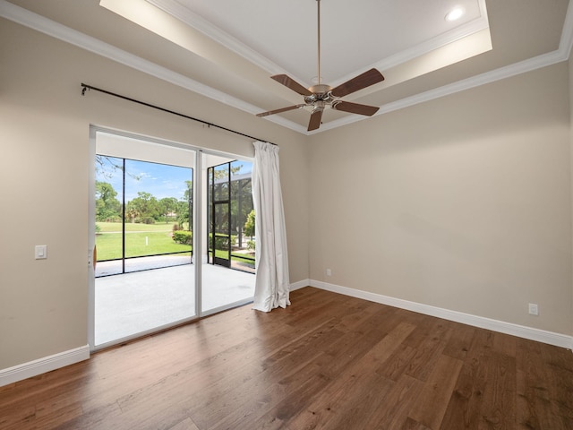 empty room with hardwood / wood-style flooring, crown molding, ceiling fan, and a raised ceiling