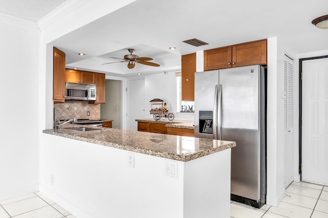 kitchen with appliances with stainless steel finishes, kitchen peninsula, ceiling fan, light stone counters, and light tile patterned floors