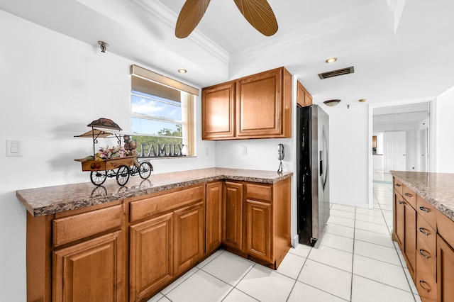 kitchen with stone countertops, ornamental molding, light tile patterned floors, and stainless steel refrigerator with ice dispenser