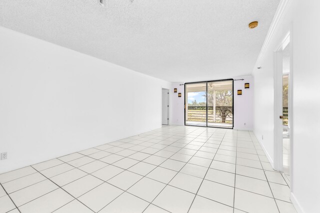 spare room featuring crown molding, light tile patterned flooring, and a textured ceiling