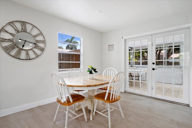 dining area featuring light wood finished floors, baseboards, and french doors