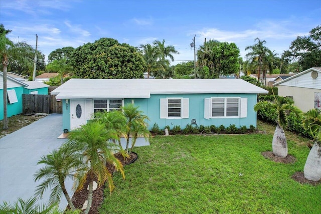 ranch-style home with driveway, fence, and a front lawn