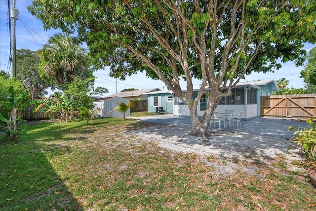 view of yard featuring a patio area, an outdoor structure, a fenced backyard, a sunroom, and a storage unit