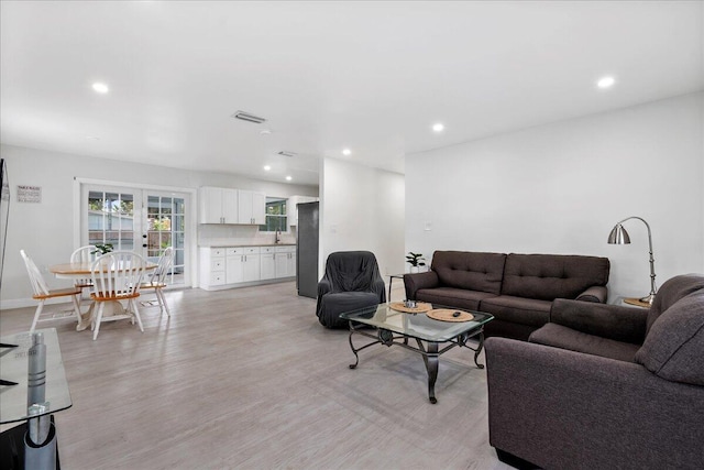living room with baseboards, visible vents, light wood-type flooring, and recessed lighting