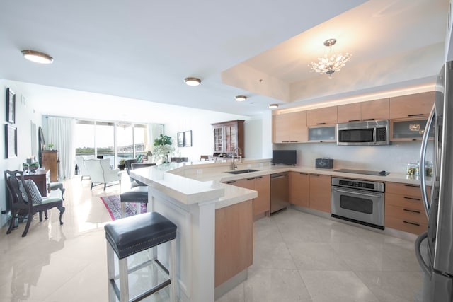 kitchen with a kitchen bar, stainless steel appliances, sink, kitchen peninsula, and light tile patterned flooring