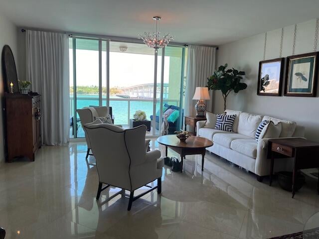 tiled living room featuring a chandelier and a water view