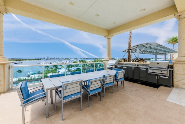 view of patio featuring area for grilling, a balcony, a water view, and a grill