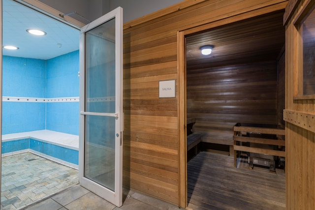 view of sauna / steam room with tile patterned flooring and wooden walls