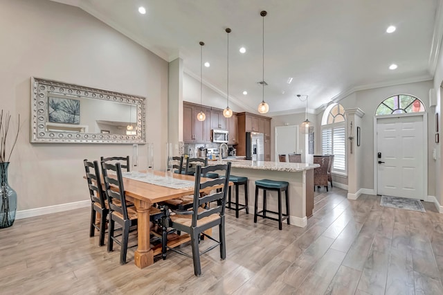 dining room featuring ornamental molding, light wood-type flooring, and lofted ceiling