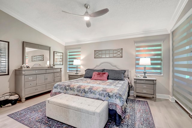 bedroom featuring a textured ceiling, ornamental molding, light wood-type flooring, and ceiling fan