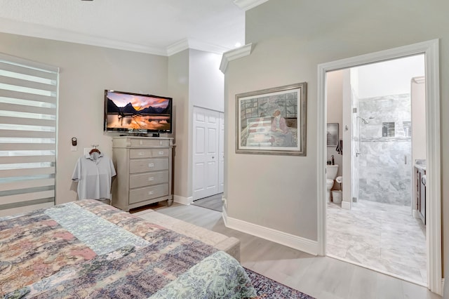 bedroom with light hardwood / wood-style floors, crown molding, and ensuite bath