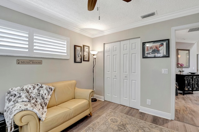 sitting room featuring ceiling fan, a textured ceiling, hardwood / wood-style flooring, and ornamental molding