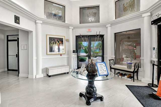 sitting room with a towering ceiling, light tile flooring, and crown molding