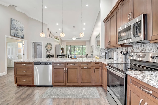 kitchen with decorative light fixtures, light hardwood / wood-style flooring, kitchen peninsula, stainless steel appliances, and backsplash