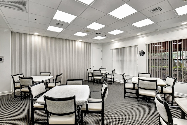 carpeted dining area with a paneled ceiling