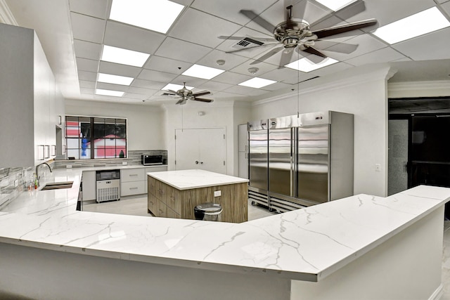 kitchen with sink, appliances with stainless steel finishes, ceiling fan, and a kitchen island