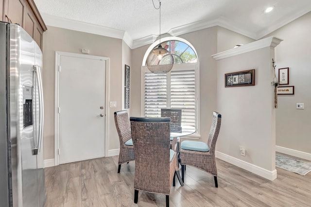 dining space with crown molding, a textured ceiling, and light wood-type flooring