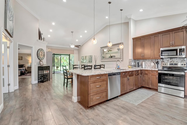 kitchen with appliances with stainless steel finishes, kitchen peninsula, decorative light fixtures, sink, and ceiling fan