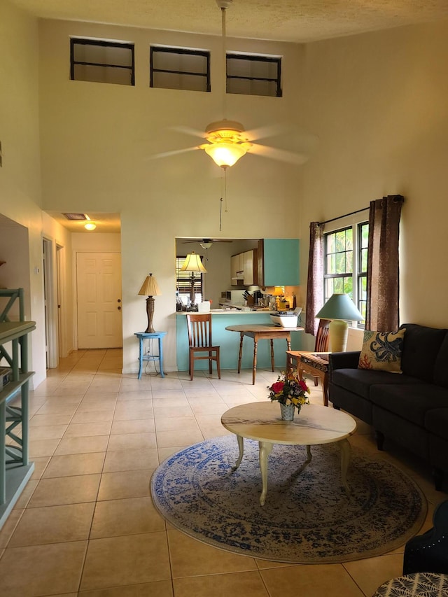 tiled living room featuring ceiling fan, a towering ceiling, and a textured ceiling