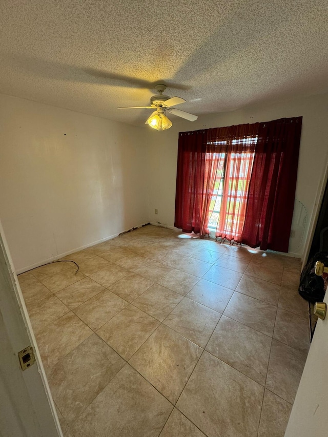 spare room with ceiling fan, light tile patterned floors, and a textured ceiling