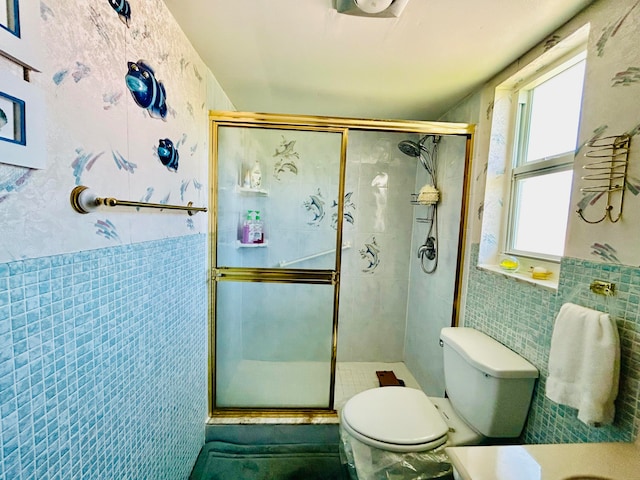 bathroom with vanity, a shower with door, toilet, and tile walls