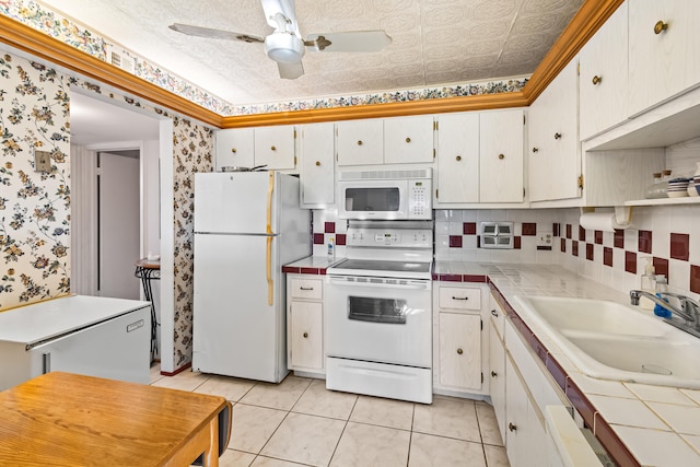 kitchen featuring ceiling fan, white appliances, sink, white cabinets, and tile counters