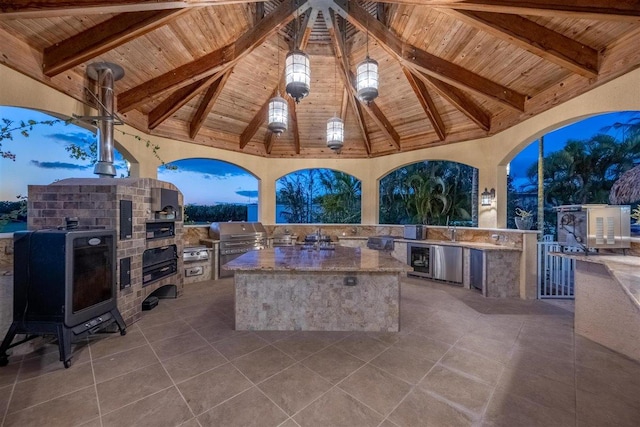 patio terrace at dusk with a gazebo, grilling area, sink, and exterior kitchen