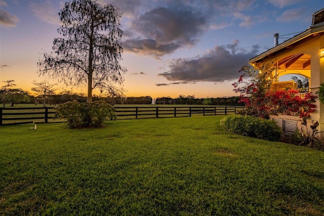 yard at dusk featuring a rural view