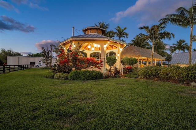 back house at dusk with a gazebo and a lawn