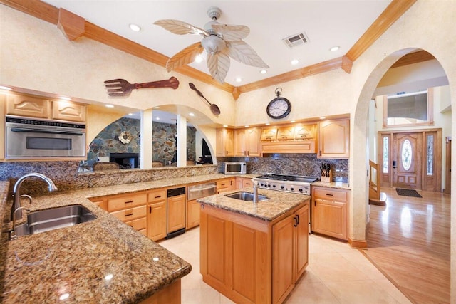 kitchen featuring ceiling fan, sink, appliances with stainless steel finishes, a center island with sink, and tasteful backsplash