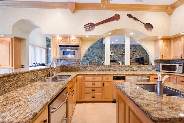 kitchen featuring appliances with stainless steel finishes, light stone counters, tasteful backsplash, and sink