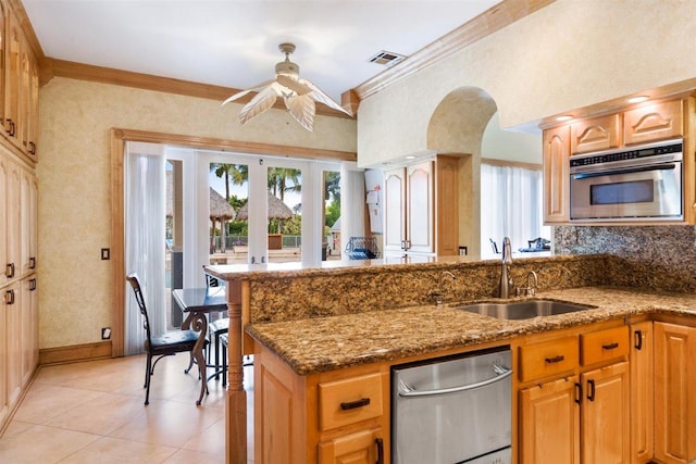 kitchen with ceiling fan, ornamental molding, appliances with stainless steel finishes, sink, and light stone counters