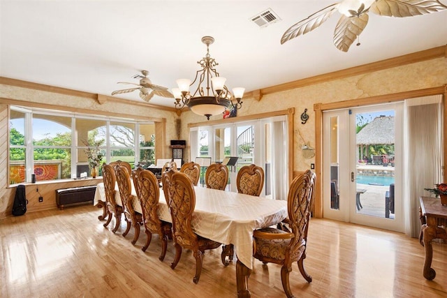 dining room with ceiling fan with notable chandelier, light wood-type flooring, and a wealth of natural light