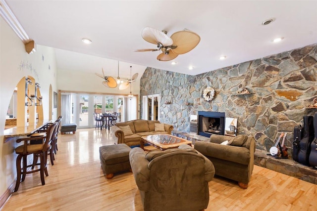 living room with light hardwood / wood-style floors, ceiling fan, and a stone fireplace