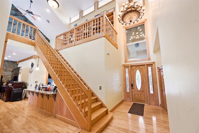 foyer entrance featuring high vaulted ceiling, ceiling fan, and light wood-type flooring