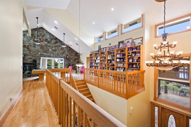 hallway featuring a chandelier, high vaulted ceiling, and light wood-type flooring