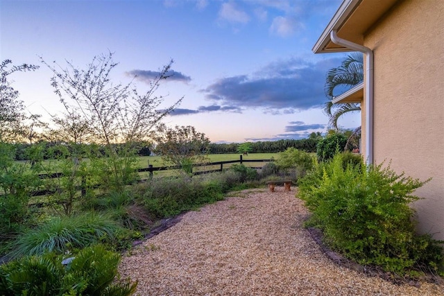 yard at dusk featuring a rural view