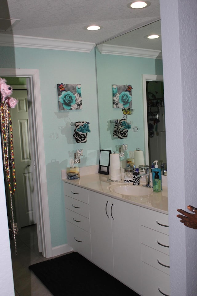 bathroom featuring a textured ceiling, ornamental molding, and vanity