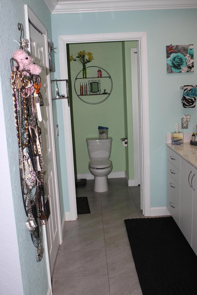 bathroom featuring toilet, tile flooring, ornamental molding, and vanity