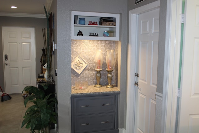 bar with light stone countertops, gray cabinetry, tile floors, and ornamental molding