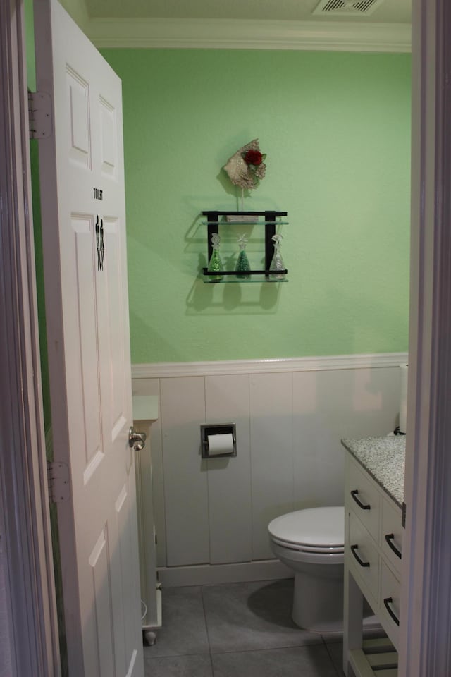 bathroom with toilet, tile flooring, vanity, and crown molding