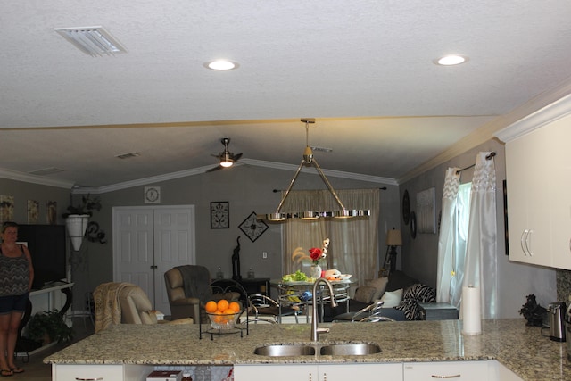 kitchen with light stone countertops, ornamental molding, white cabinetry, and sink