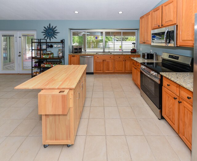 kitchen featuring sink, light tile patterned floors, appliances with stainless steel finishes, wood counters, and french doors