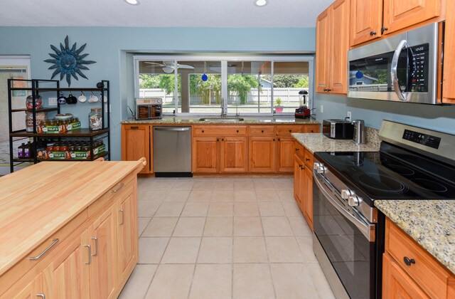 kitchen with light stone counters, stainless steel appliances, sink, and plenty of natural light